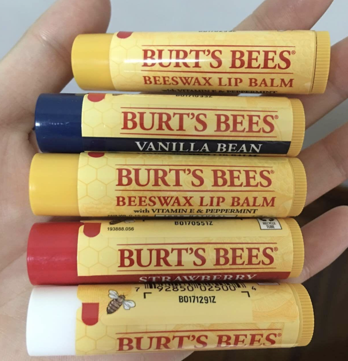 reviewer holding four lip balms in different flavors in hand