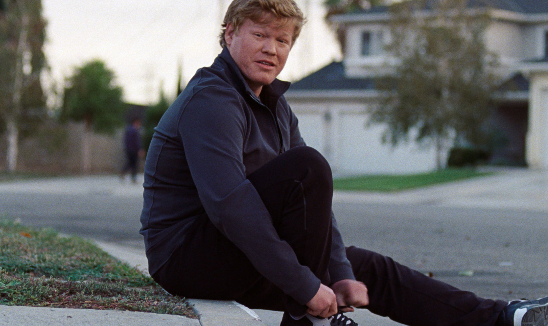 Jesse Plemons tying his shoe while looking at the camera