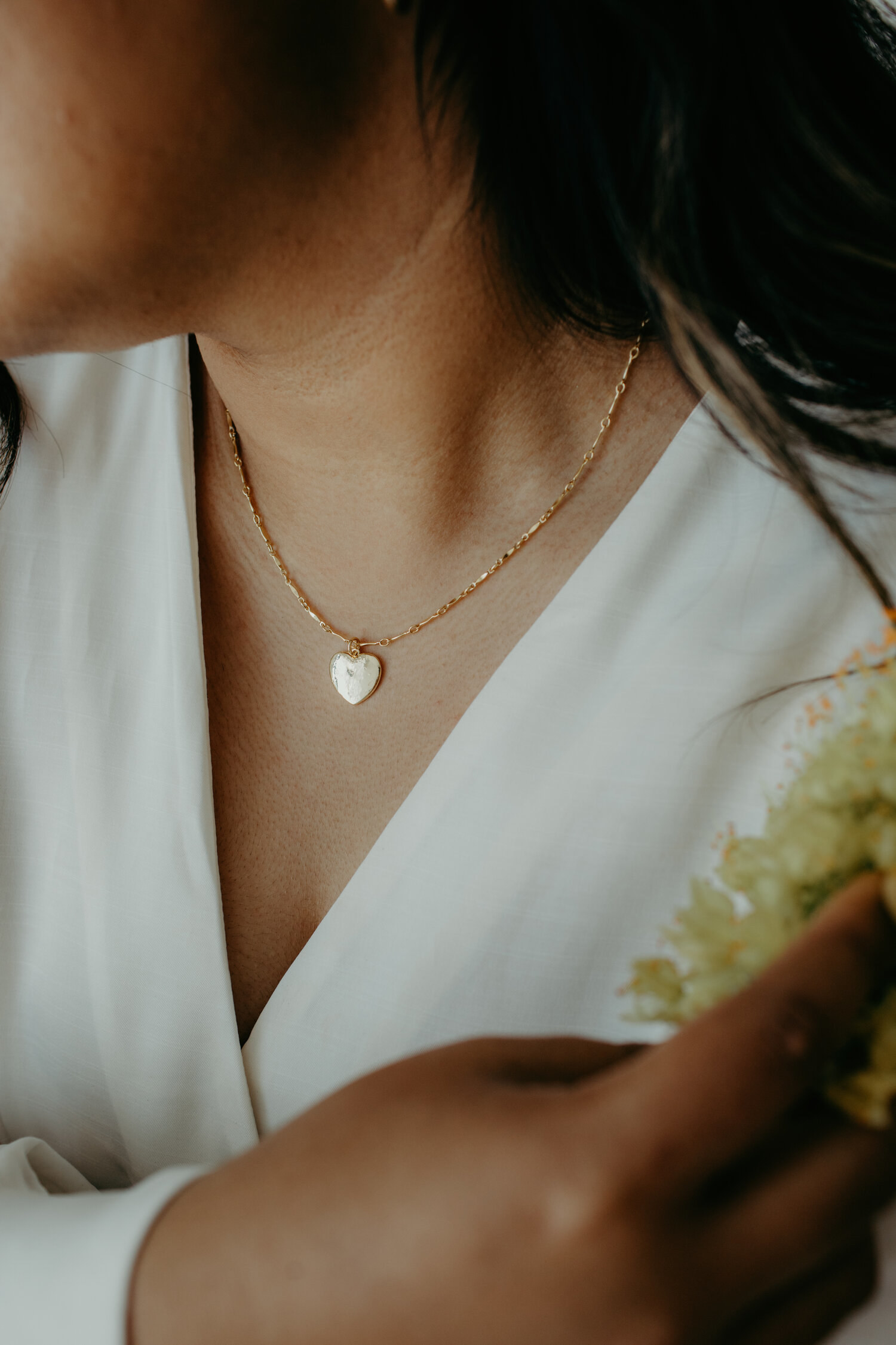 a model wearing a gold necklace with a charm of a heart