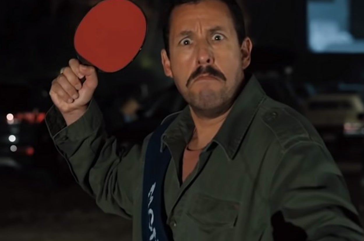 hubie holds a table tennis paddle up, frowning with eyes wide