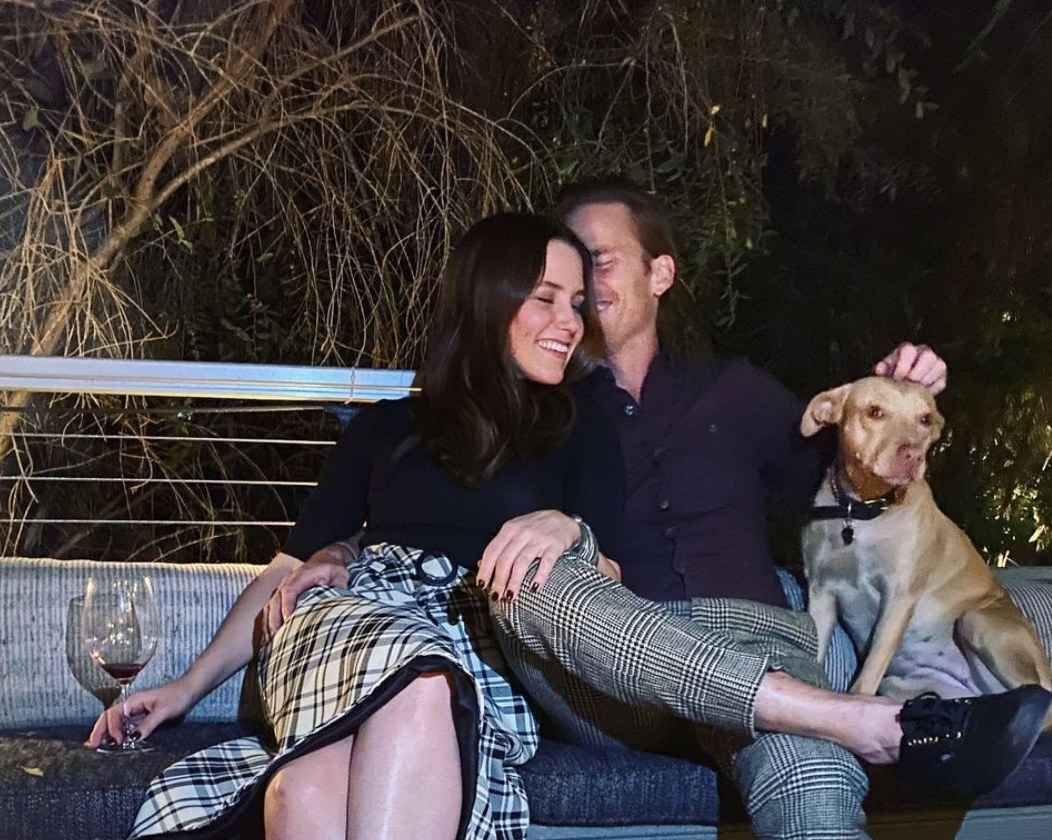 Sophia and Grant cozy up on a couch outside with a dog sitting nearby