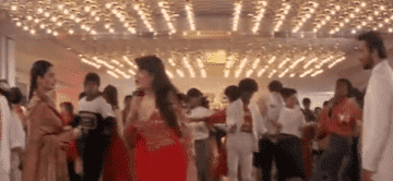 Nandini, and several background dancers dance while sanjay sips on champagne and aarti smiles