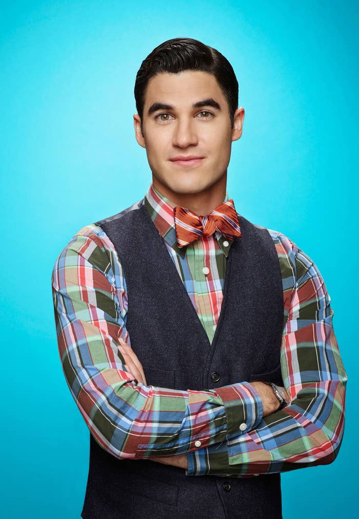 Darren Criss poses with his arms crossed in a promotional image for Glee