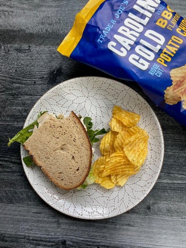 A bag of Carolina gold BBQ potato chips and a sandwich on a plate