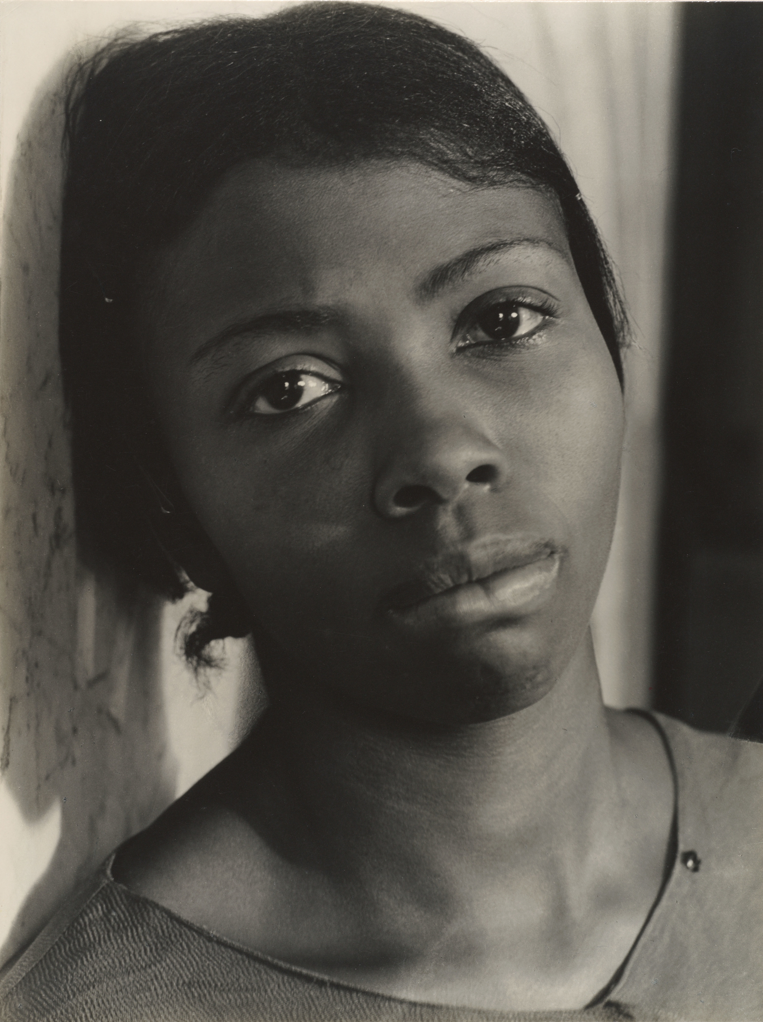 A woman with short hair looks directly at the camera, close up