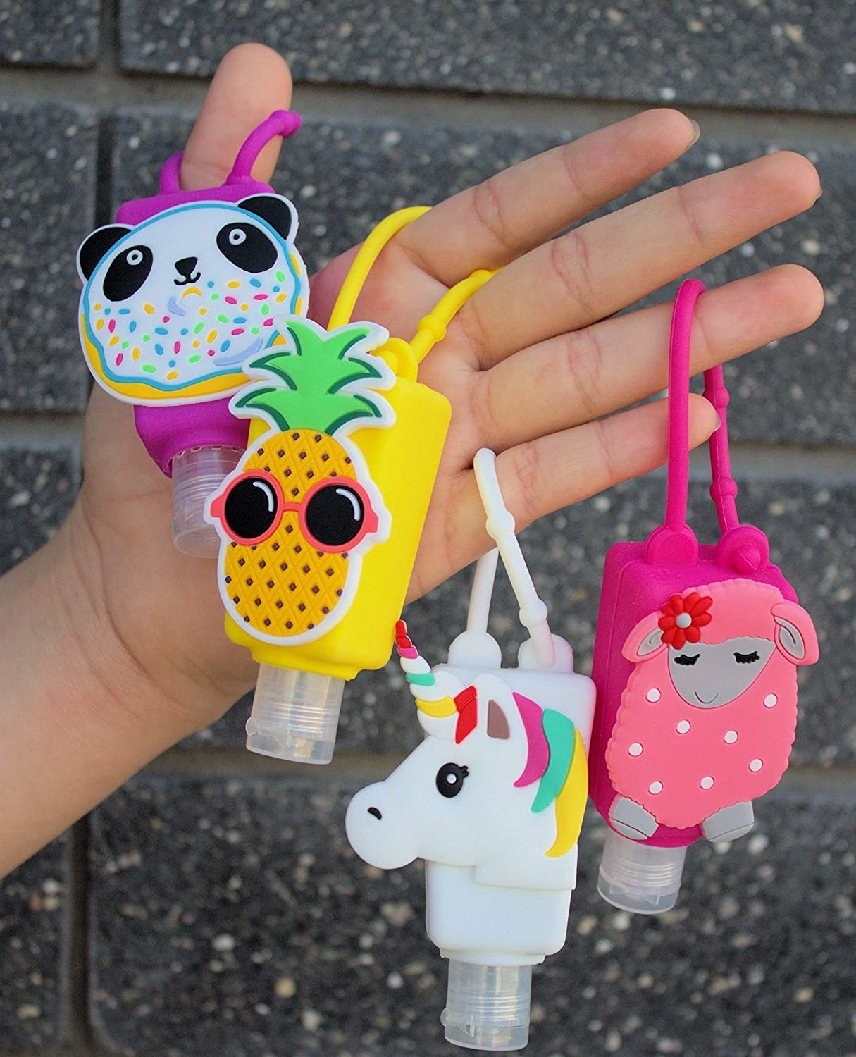 a person holding four cute sanitizer keychain bottles