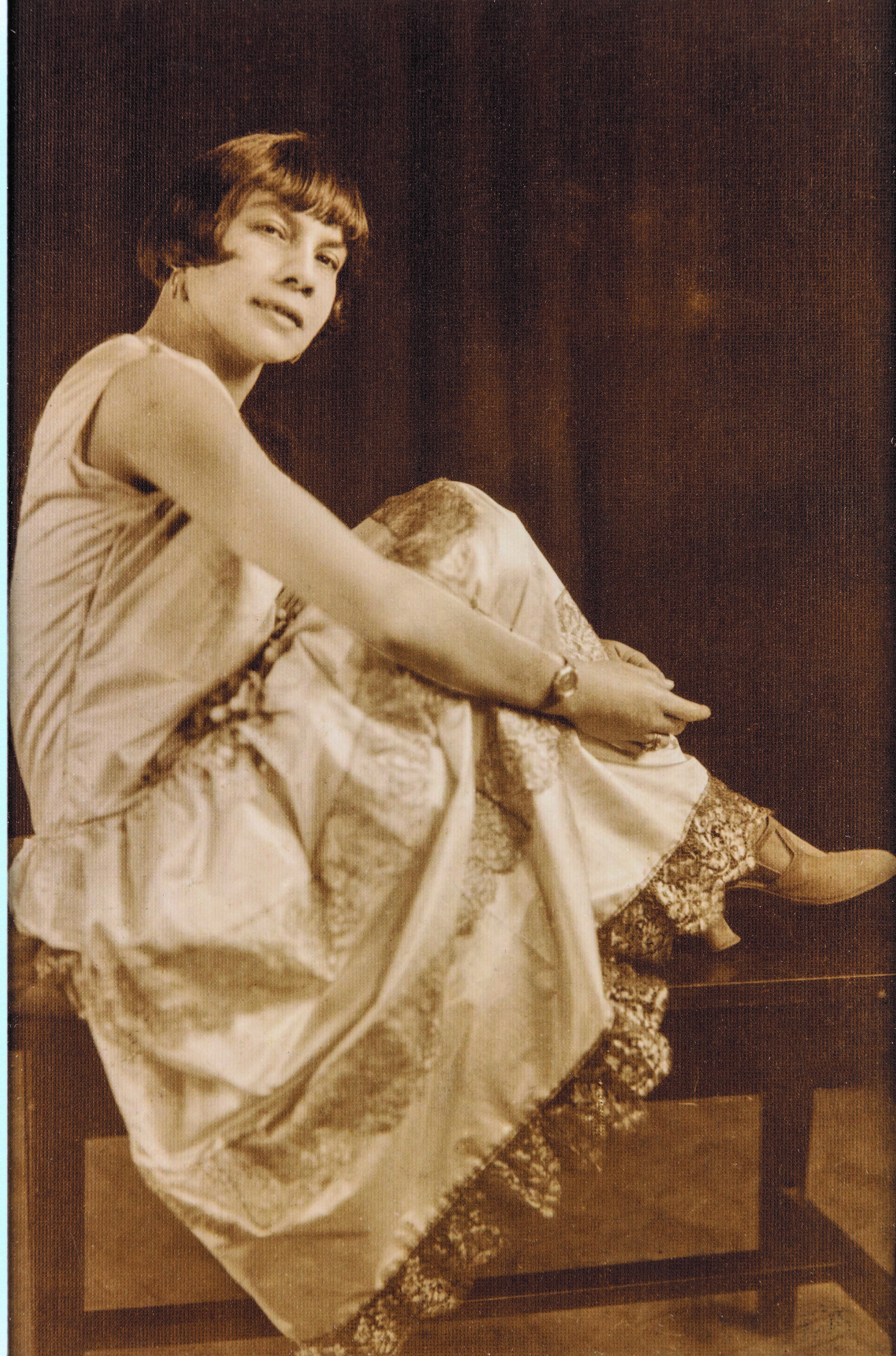 A woman in an evening dress sitting with her feet up on a bench, looking past the camera