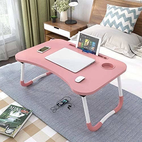 A folding table on a bed with multiple devices on it
