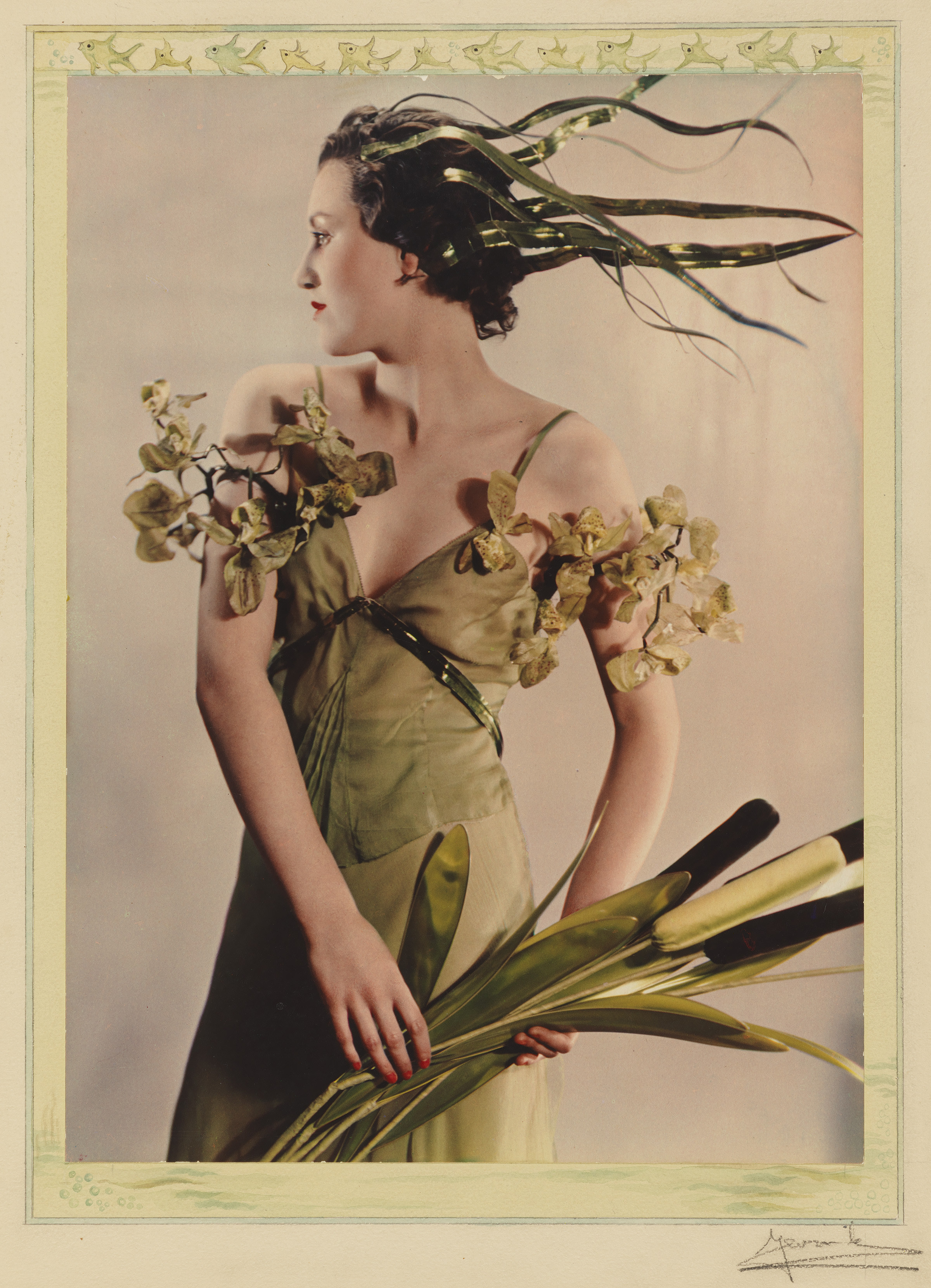 A woman in a green flowing costume holds a spray of cattails