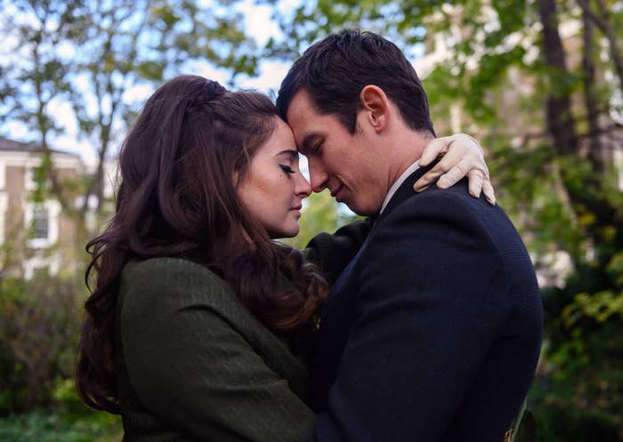 Sideview of Jennifer in an overcoat embracing Anthony in suit, faces touching, in a park