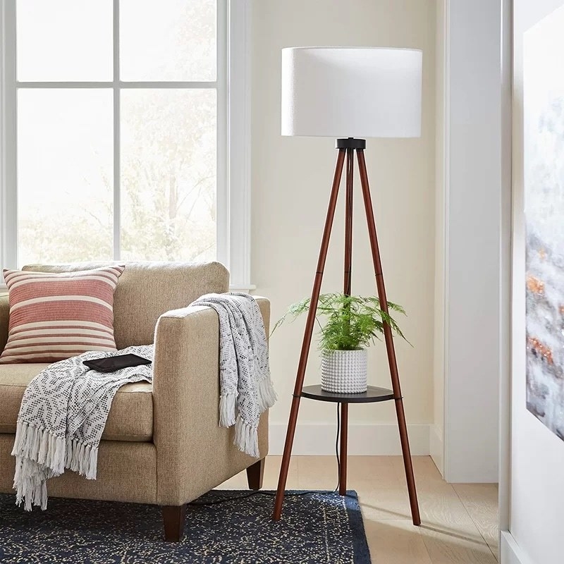 A tripod lamp with plant on its built in shelf
