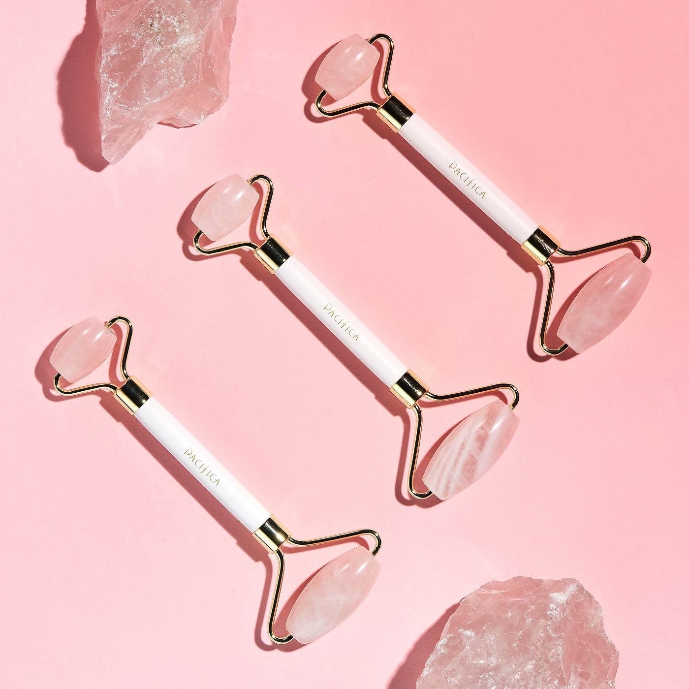 A row of three rose quartz facial rollers