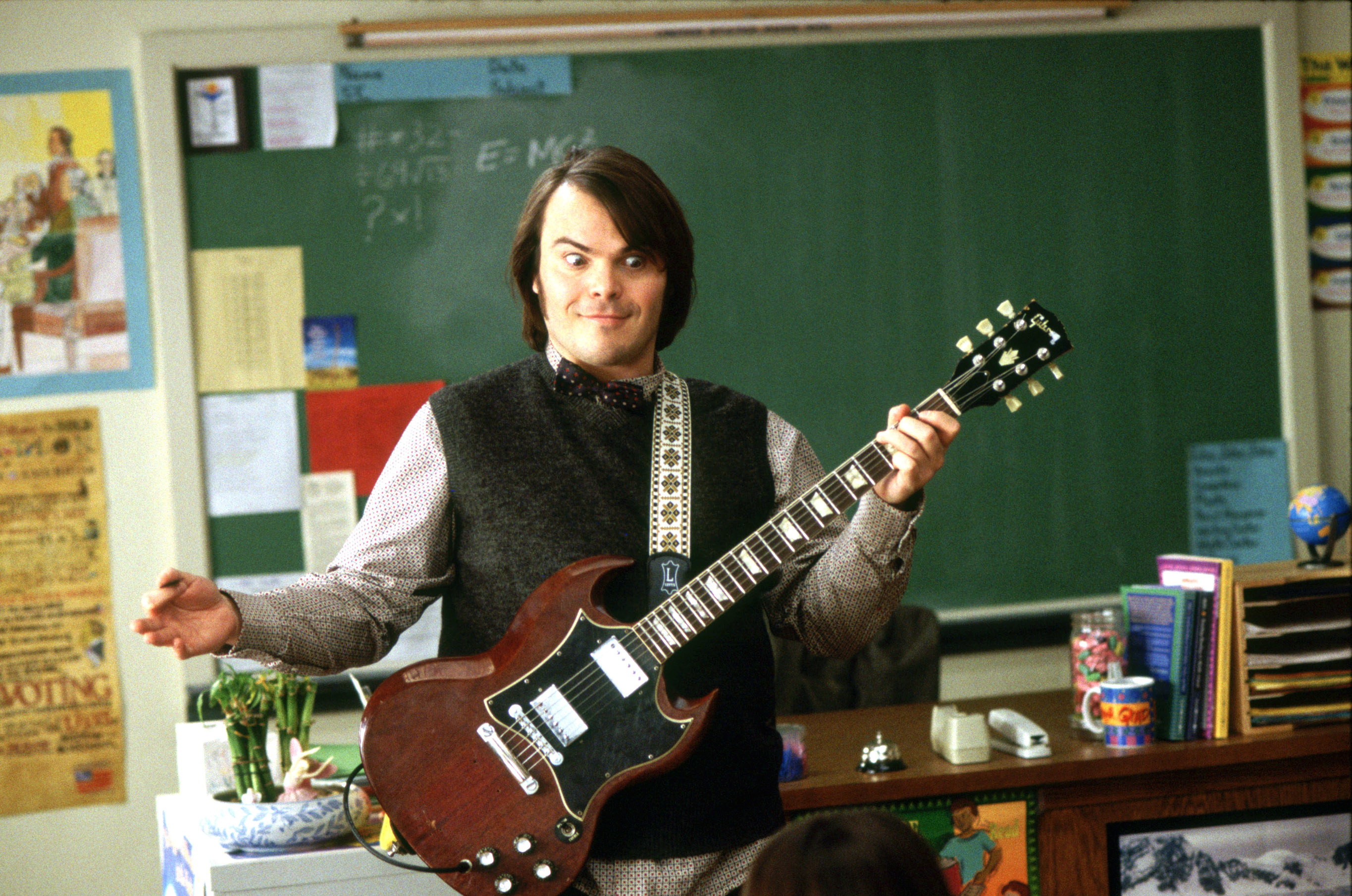Jack Black with his arms open brandishing a guitar