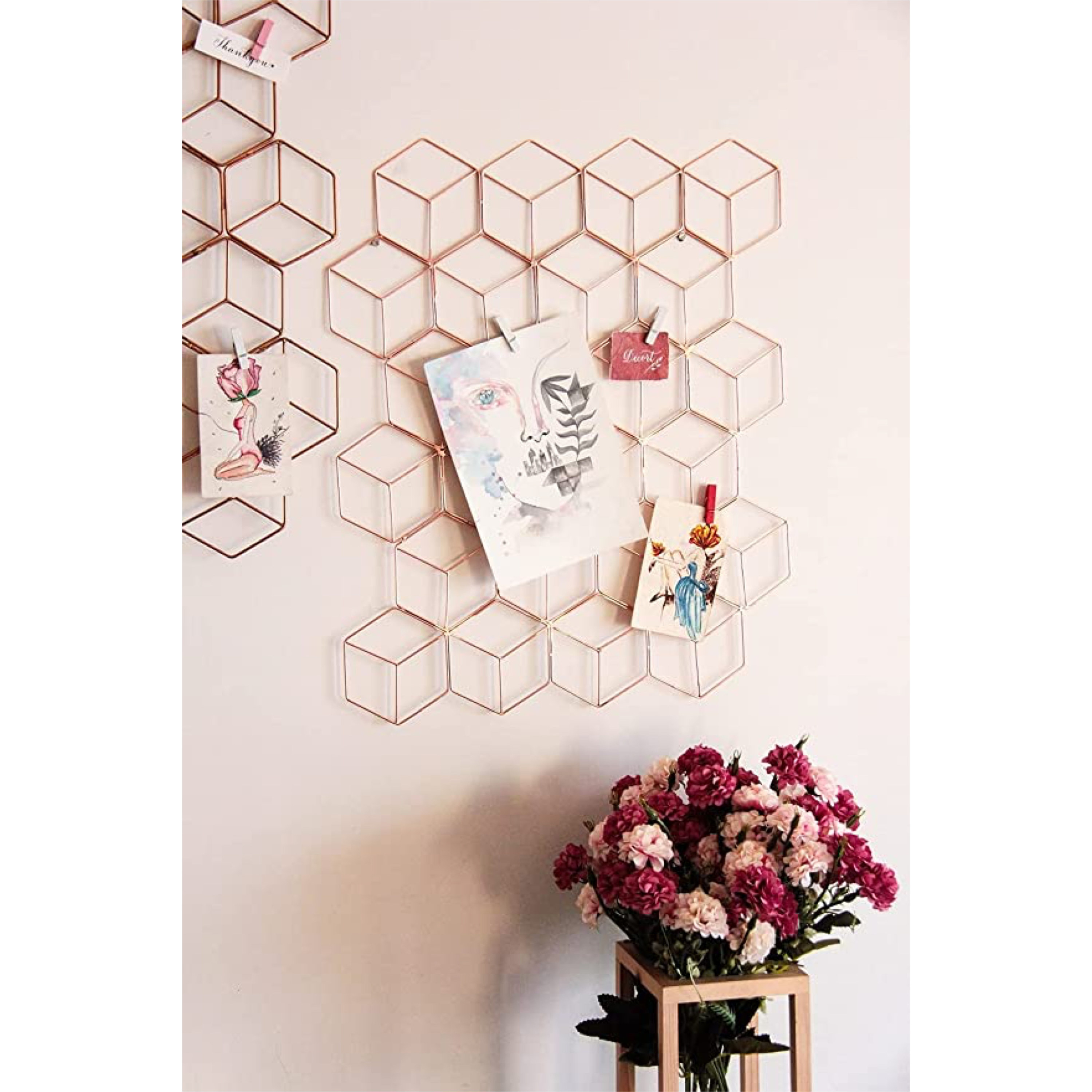 A hexagonal metal grid hanging on a wall above a bouquet of flowers