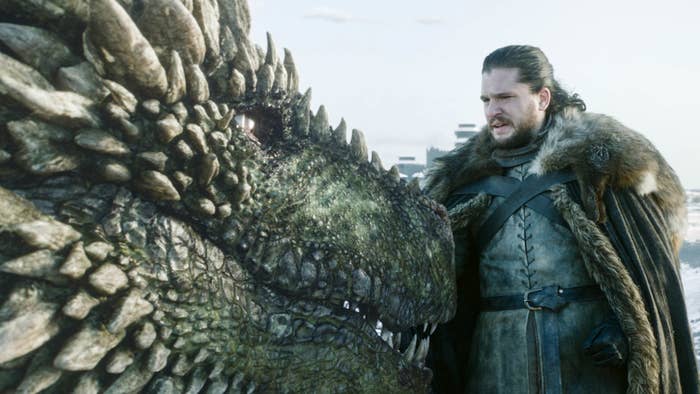 Kit Harington in the show game of thrones petting a dragon