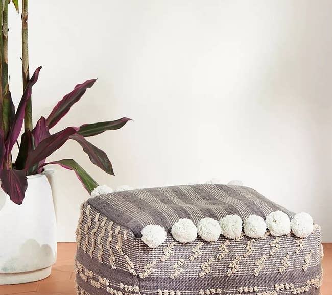 gray pouf with tassel details in cube shape