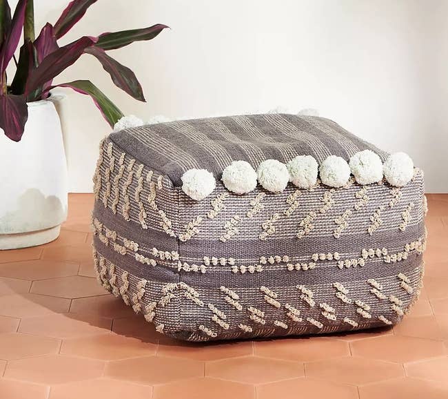 gray pouf with tassel details in cube shape