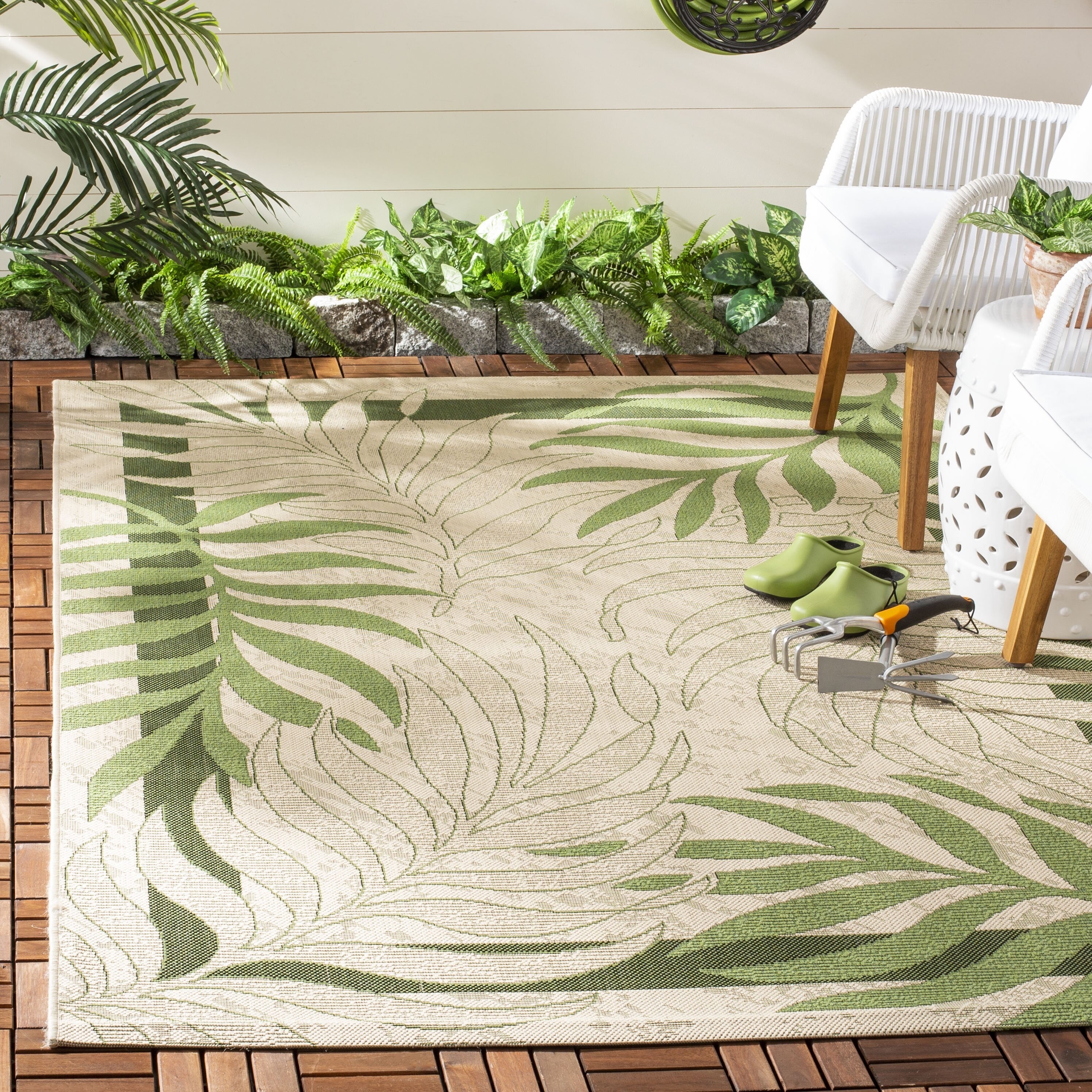 decorative rug on a patio. it has a large palm leaf pattern repeating throughout.