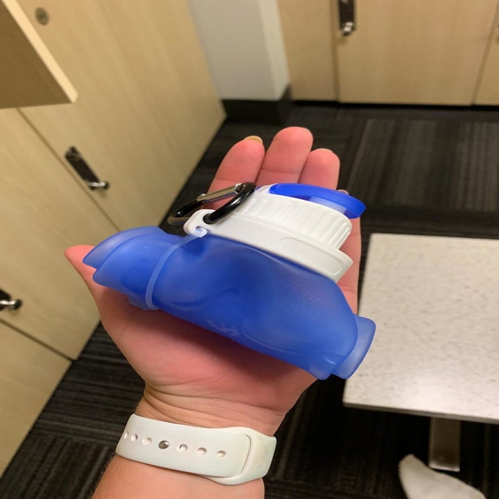 hand holding the empty water bottle with clip rolled up to palm size