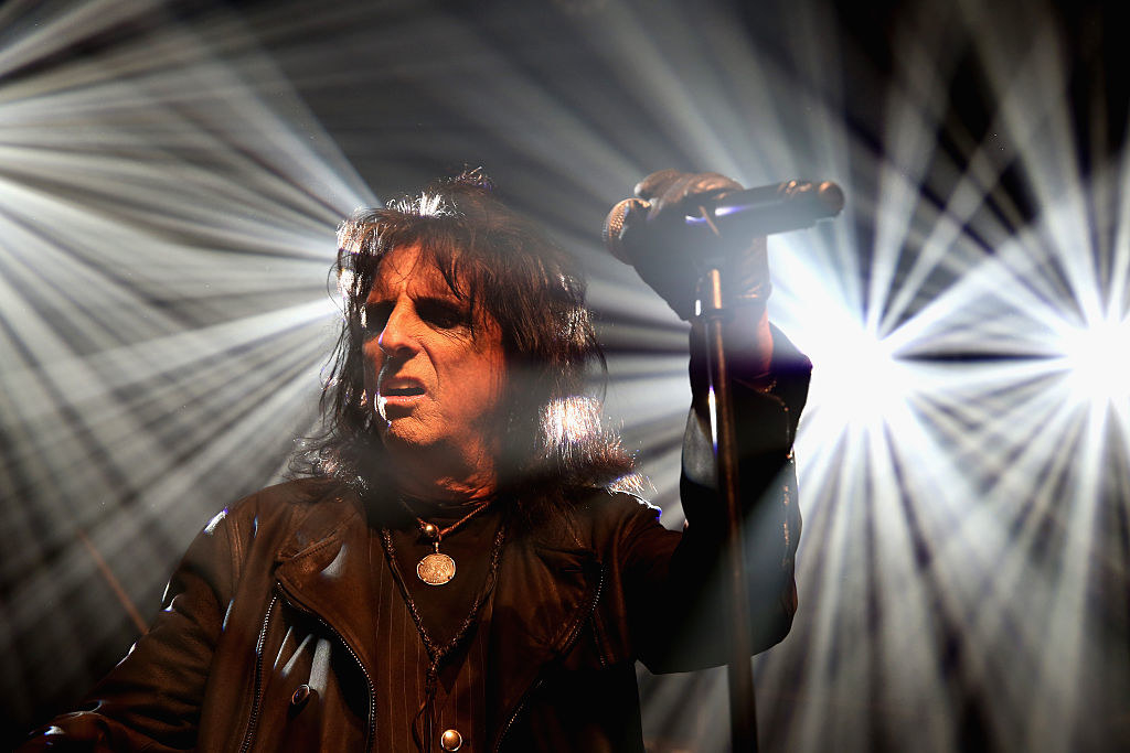 Alice Cooper onstage with bright lights behind him