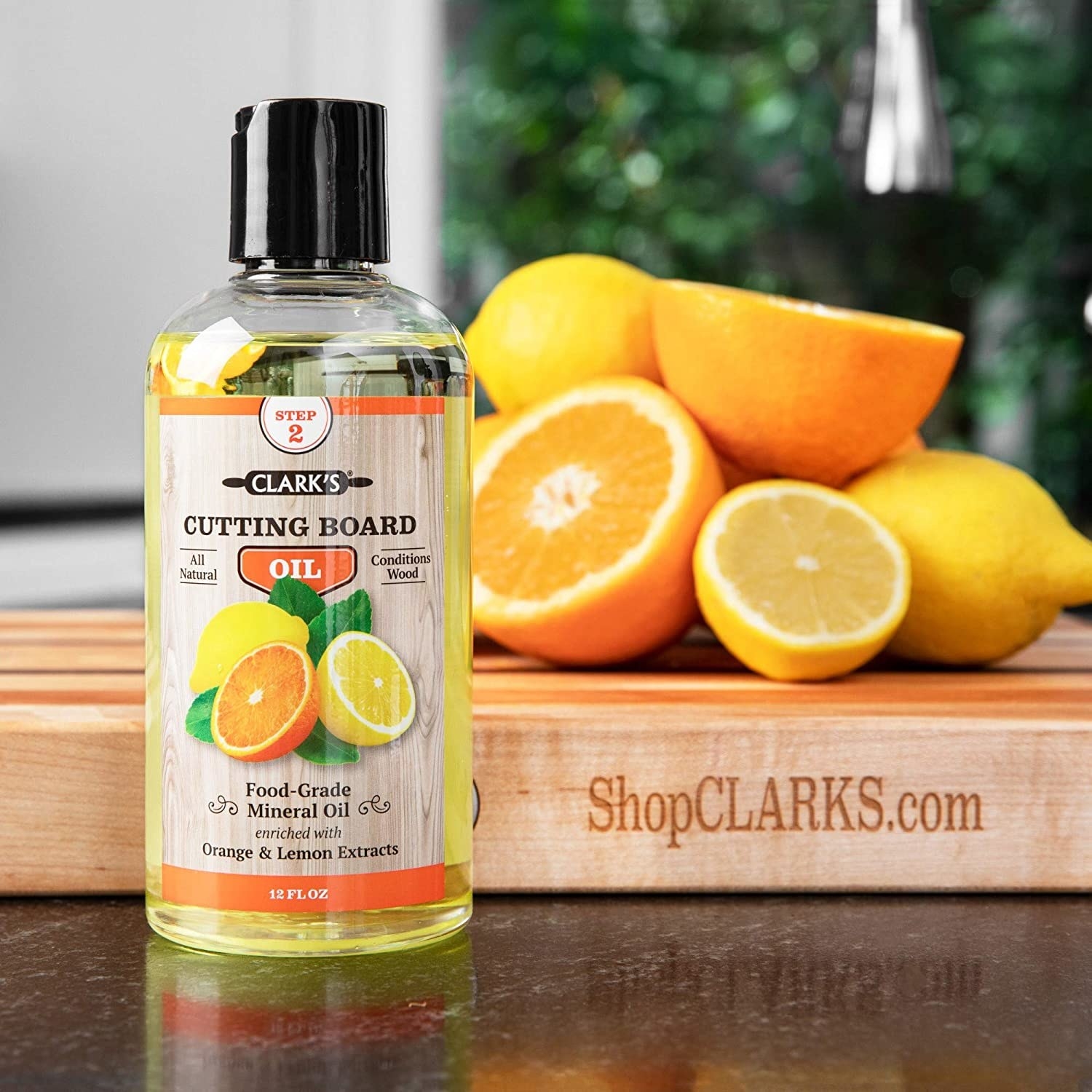 a bottle of cutting board oil in front of a cutting board with citrus on top