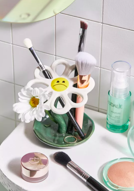 A daisy-shaped brush holder where the petals are open to thread a handle through