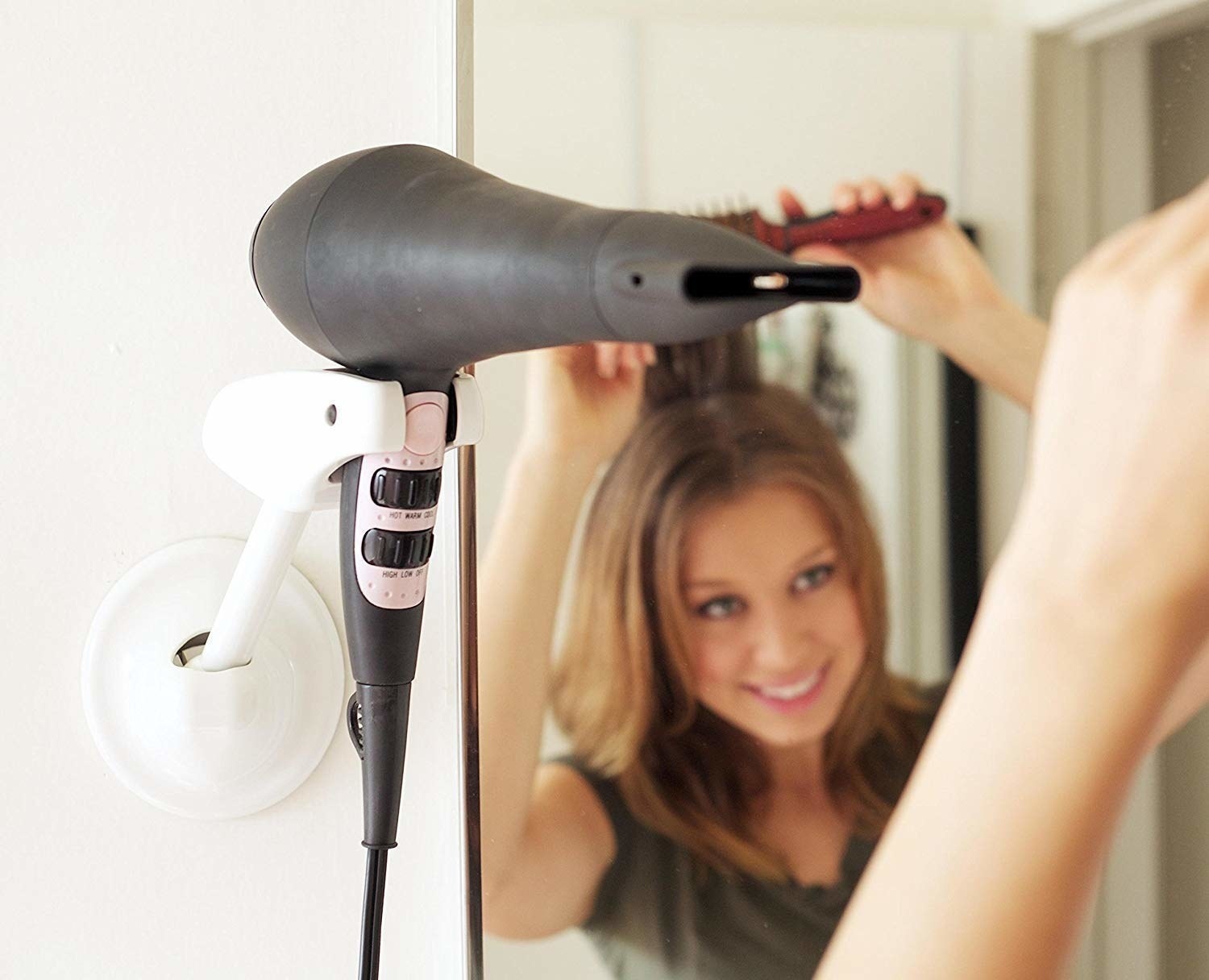 person blow drying hair with a dryer placed in the holder