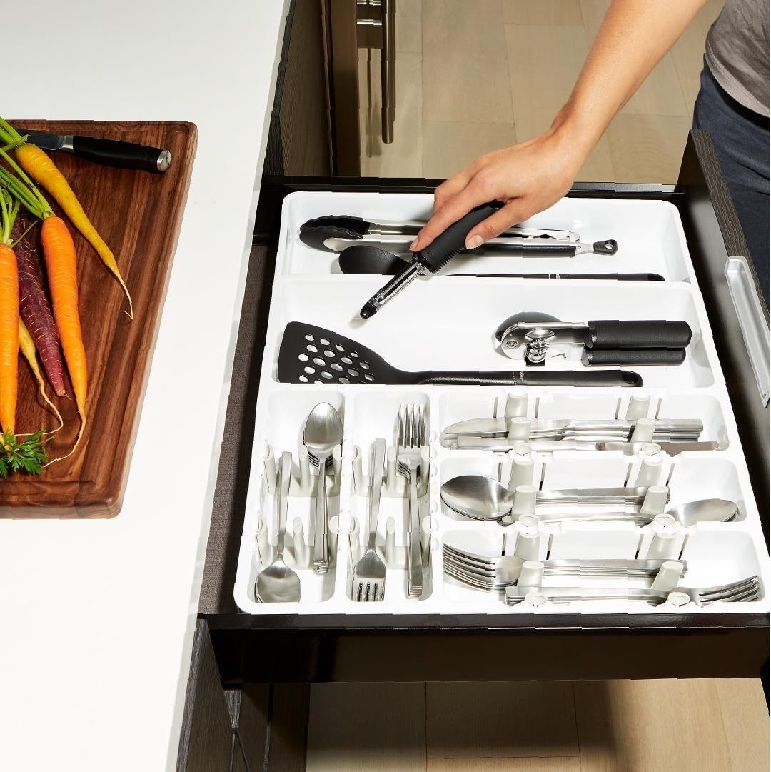 A person putting a utensil into the expanding organizer