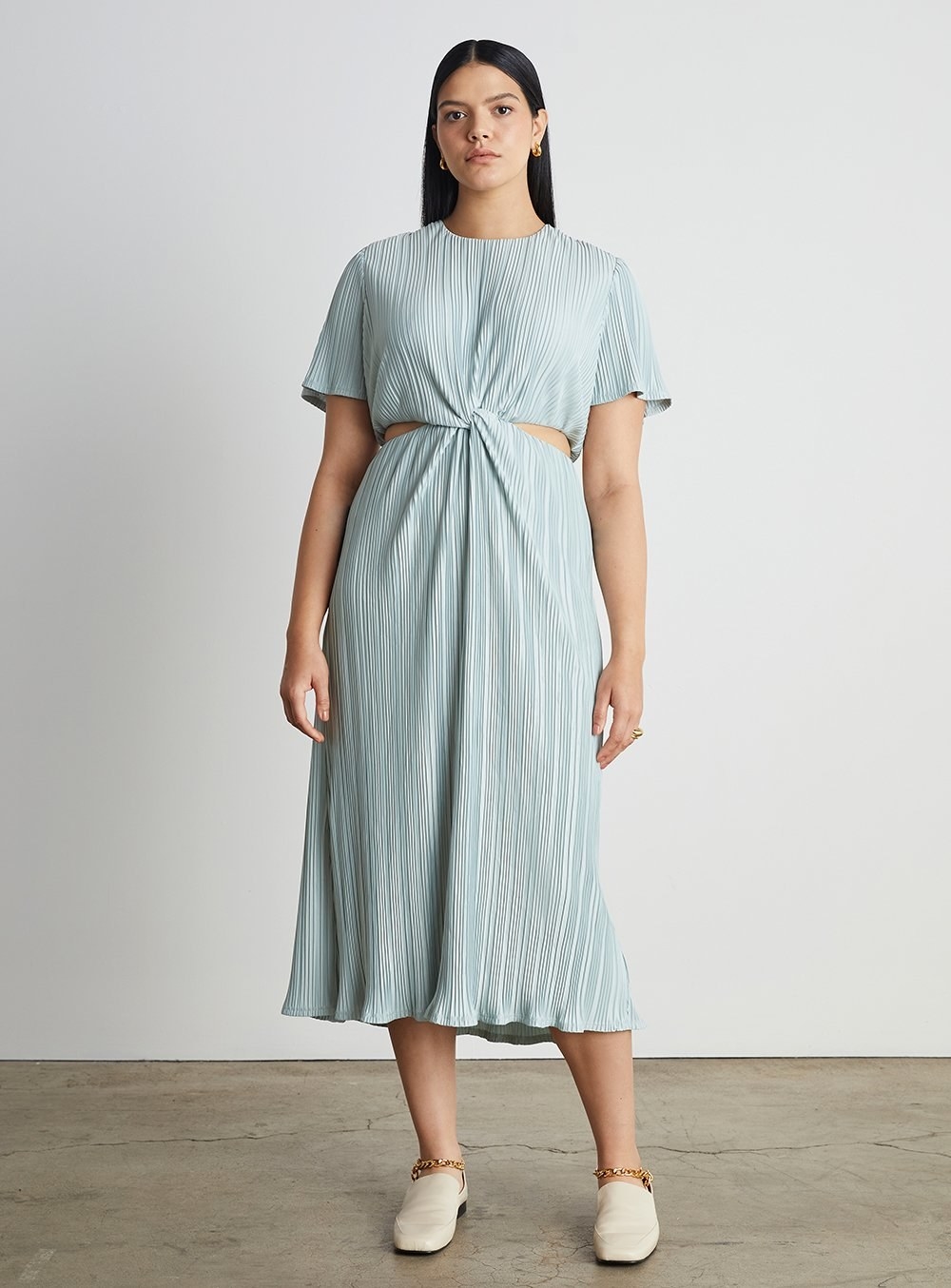 model wearing the midi pleated dress with short-sleeves and cut out sides and back in a light blue