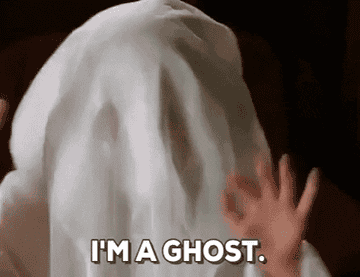 A person acting like a ghost by covering themselves with a white sheet