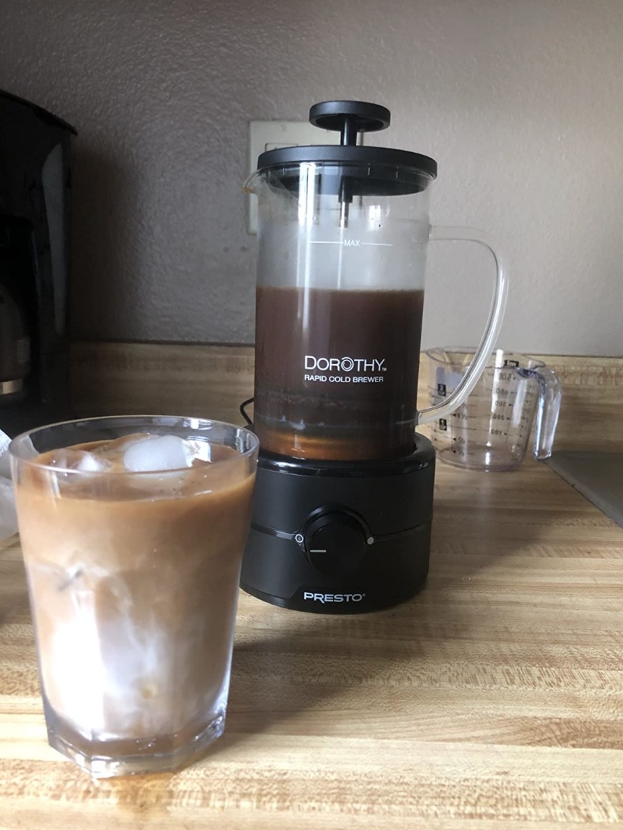 the cold brew maker next to a reviewer&#x27;s cup of iced coffee