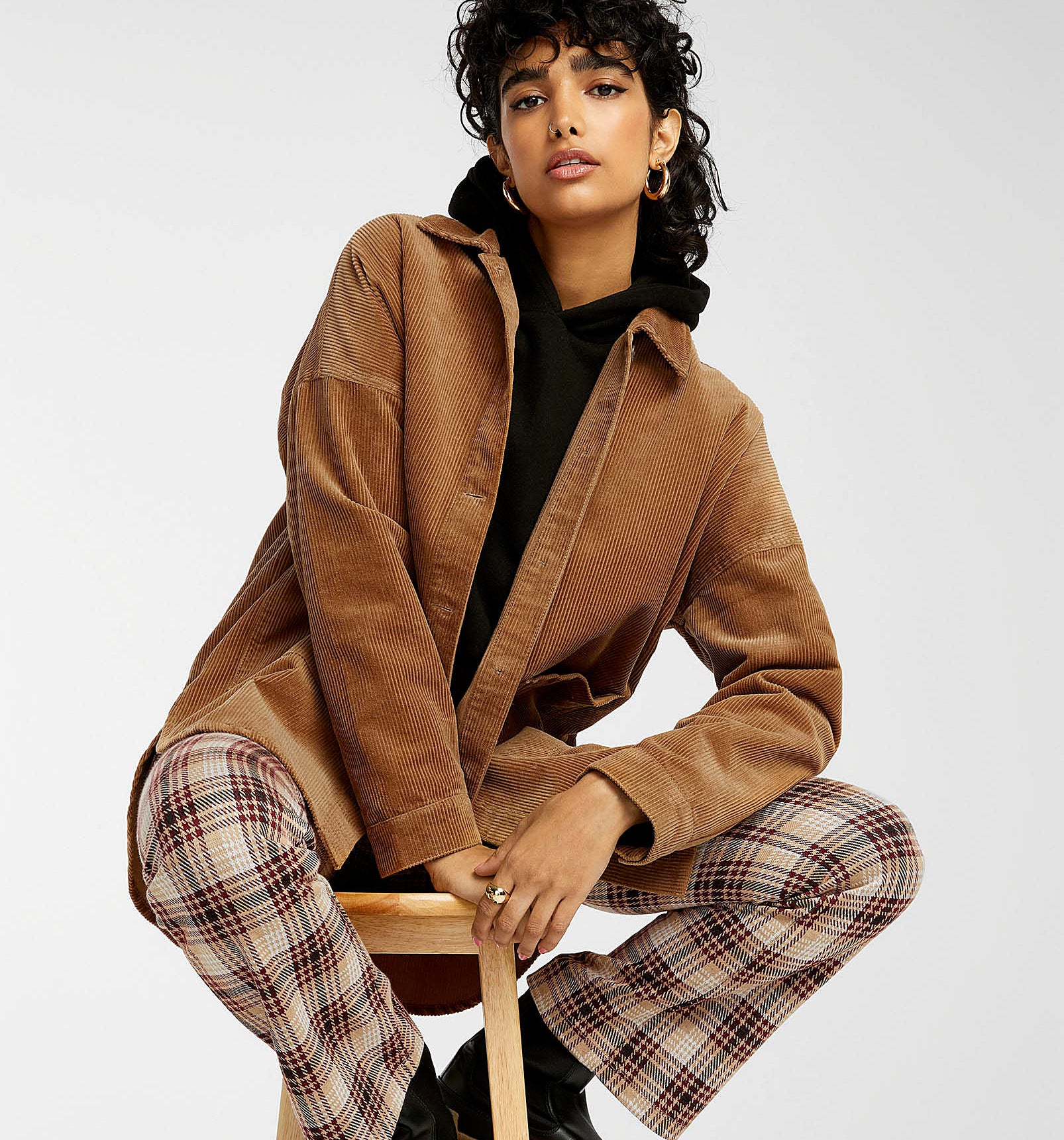 a person sitting on a stool wearing the corduroy jacket with checkered pants and rain boots