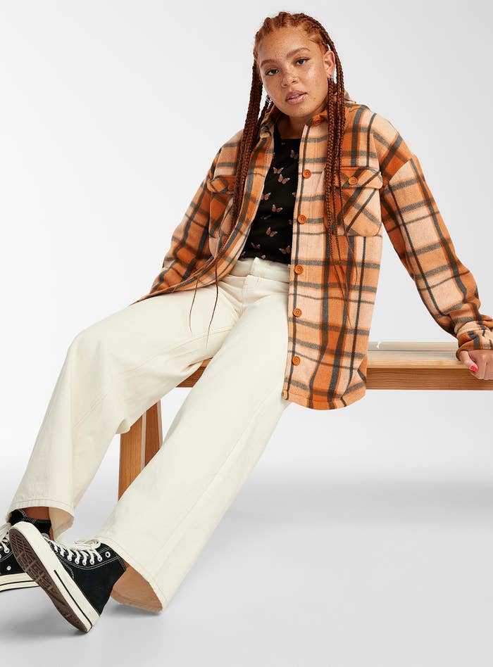 a person wearing the flannel shirt jacket with a t-shirt, white pants, and converse