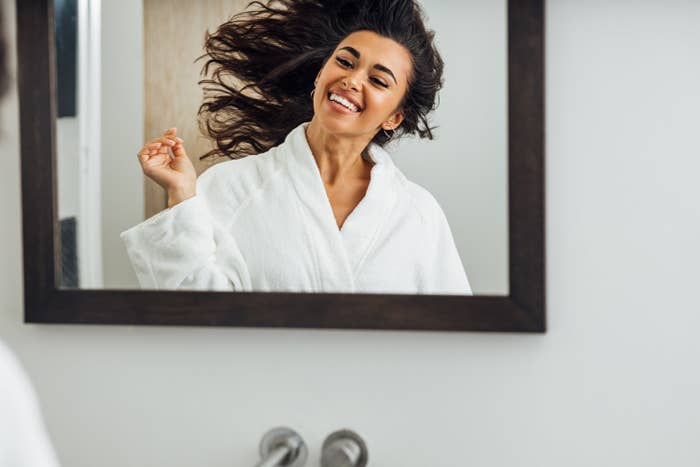 Woman in bathrobe smiles in mirror