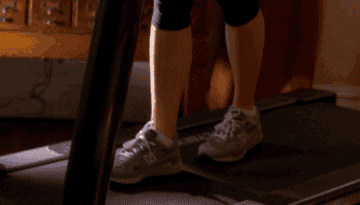 gif of Tina Fey on a treadmill walking slowly while eating ice cream that reads whoooo as if she is working out really hard