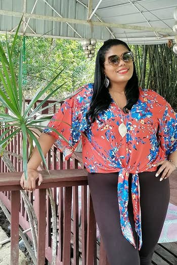 a reviewer wearing the shirt in red with a blue floral print 