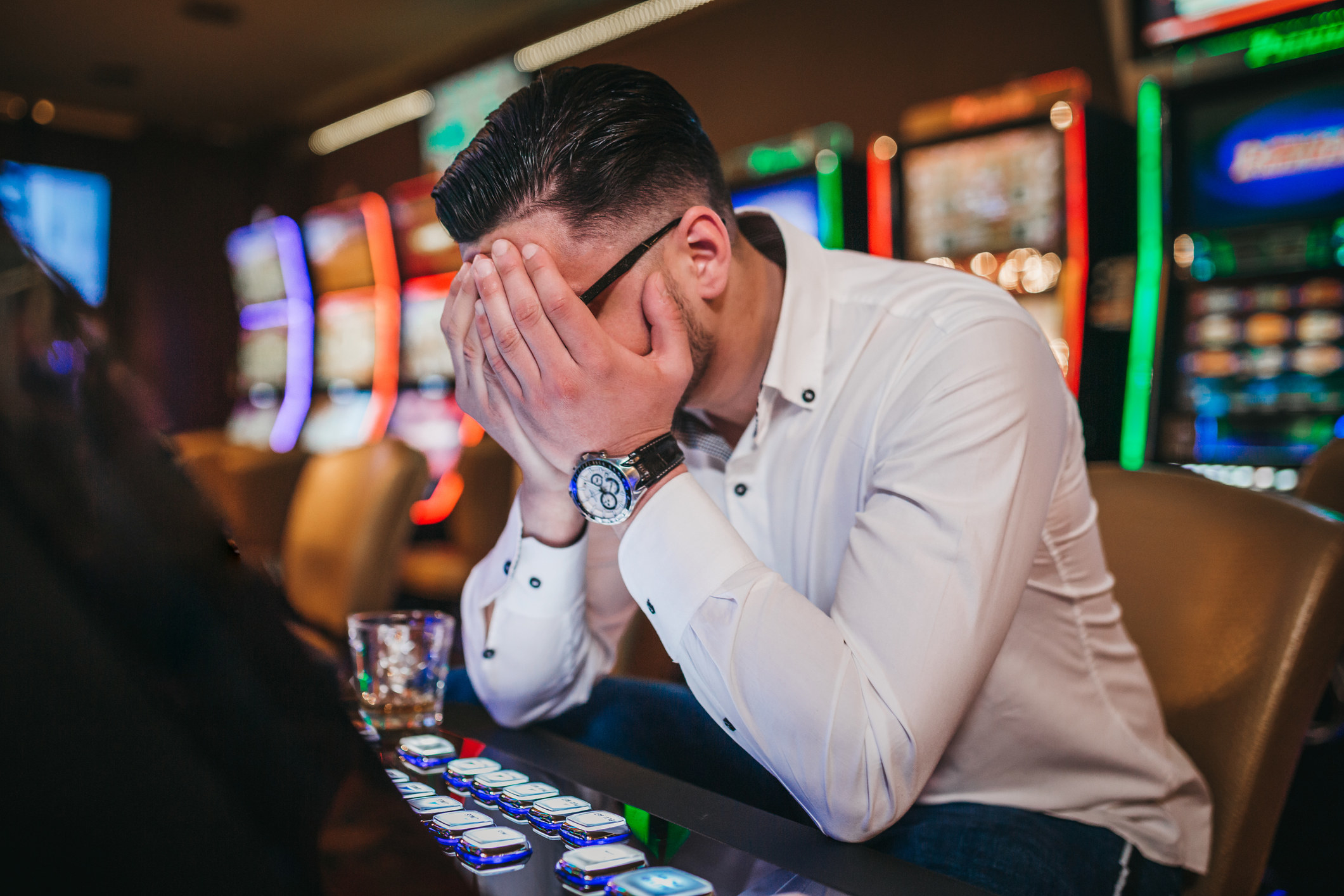 Person sitting at a video poker game with their head in their hands