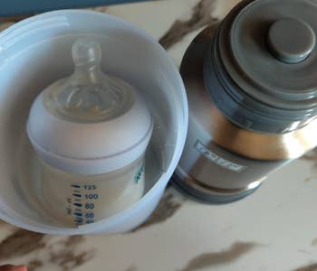 Reviewer using the travel warmer to heat up a baby bottle