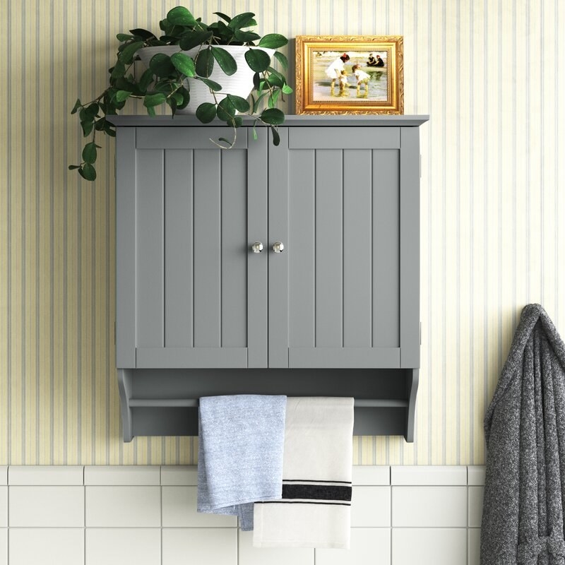 The cabinet in gray mounted on the wall in a bathroom