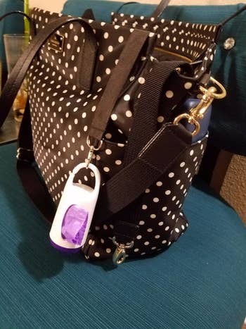 Reviewer's photo showing the disposable bag dispenser clipped onto their diaper bag