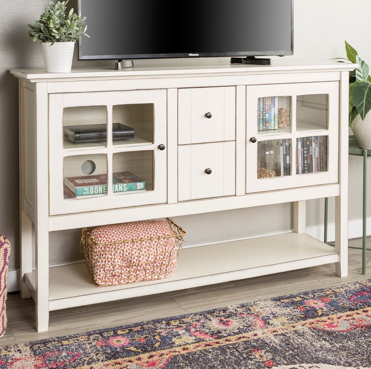 The TV stand with multiple items stored inside and a TV on top