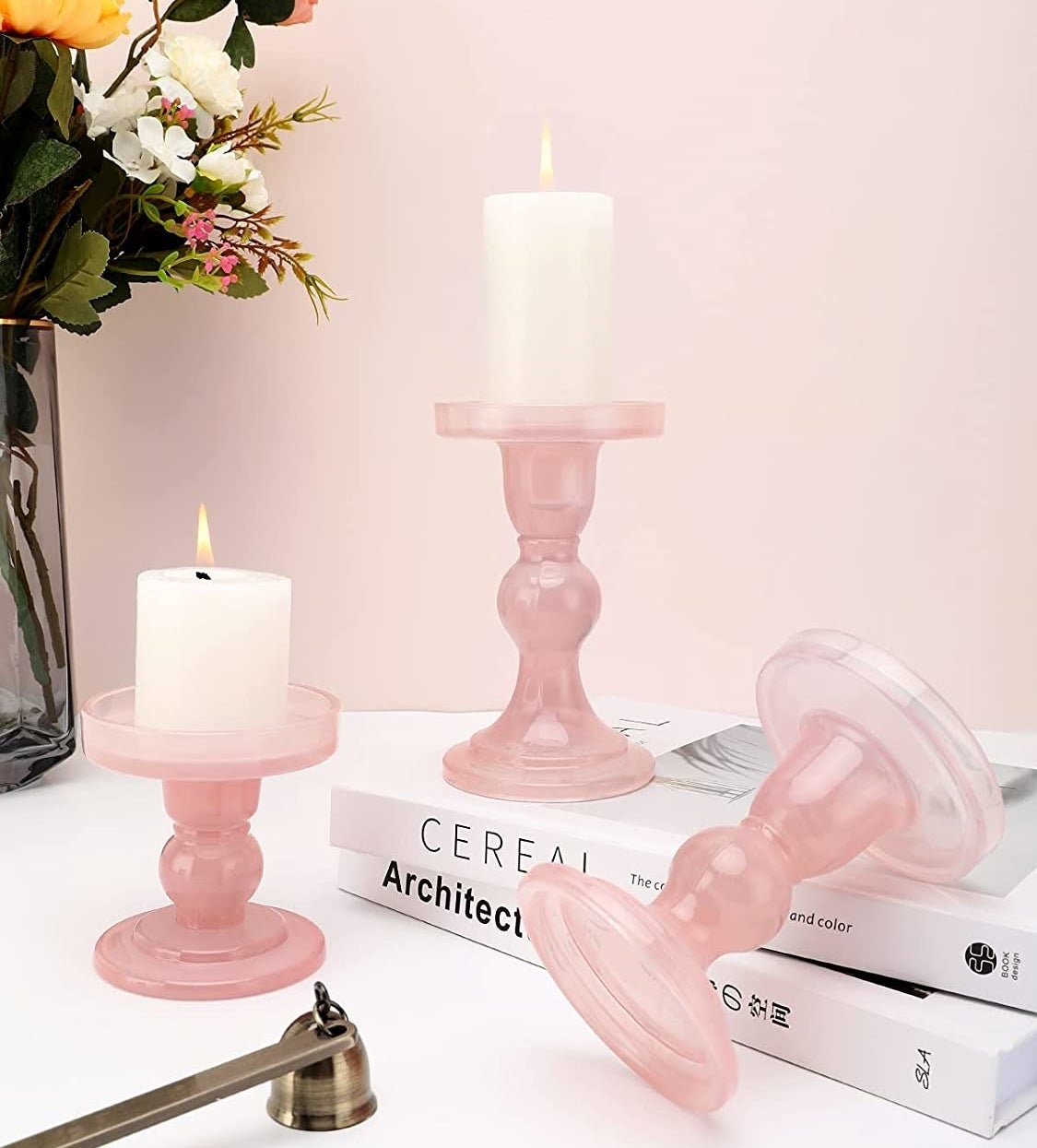 The three candle holders with candles on them on top of books