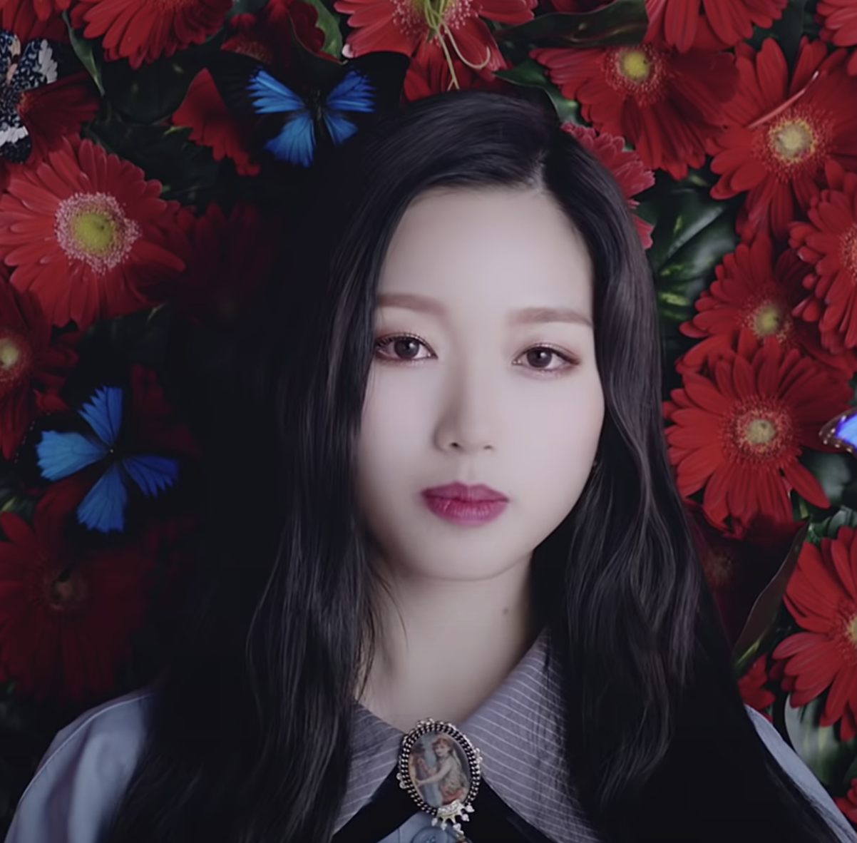 Go Won stands in front of a wall of flowers and butterflies