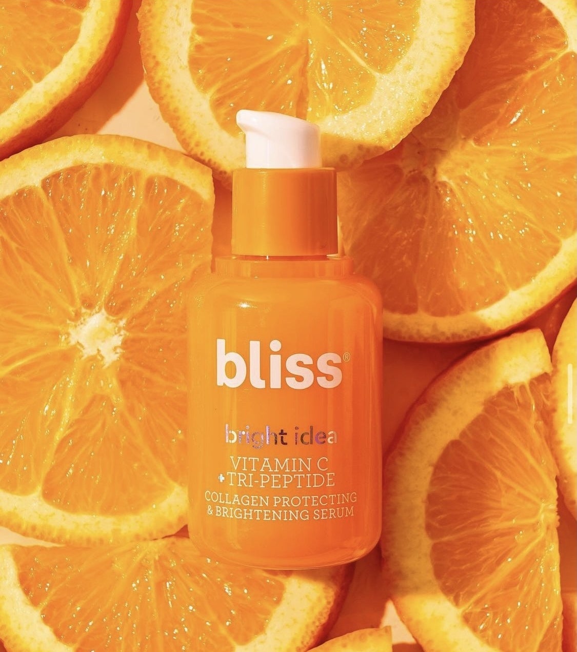 A bottle of Bliss vitamin C serum on a pile of orange slices