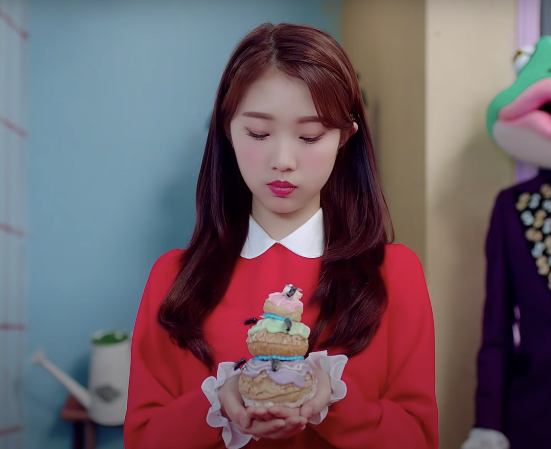 YeoJin holds a cake in her hands covered in flies