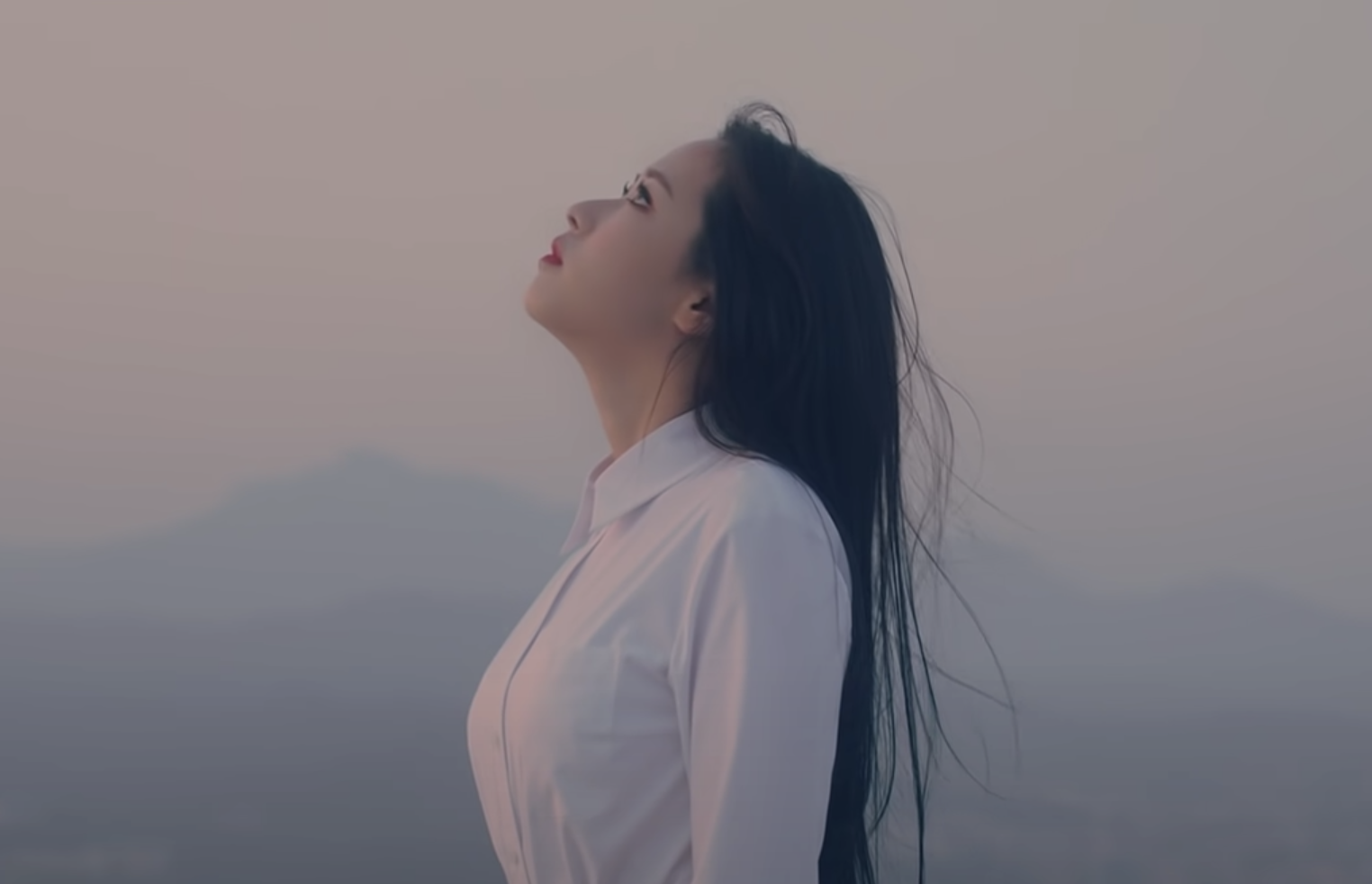 Olivia Hye stands on a rooftop and looks out at the city that surrounds her