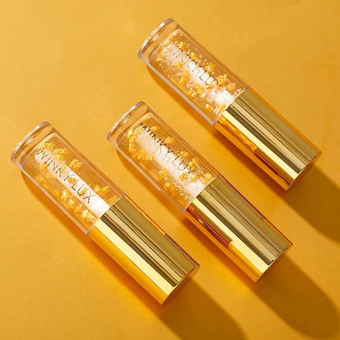 A row of three lip oils on a yellow backdrop