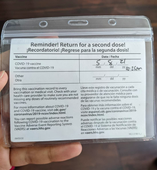 A customer review photo of them holding their vaccination card with the plastic protector