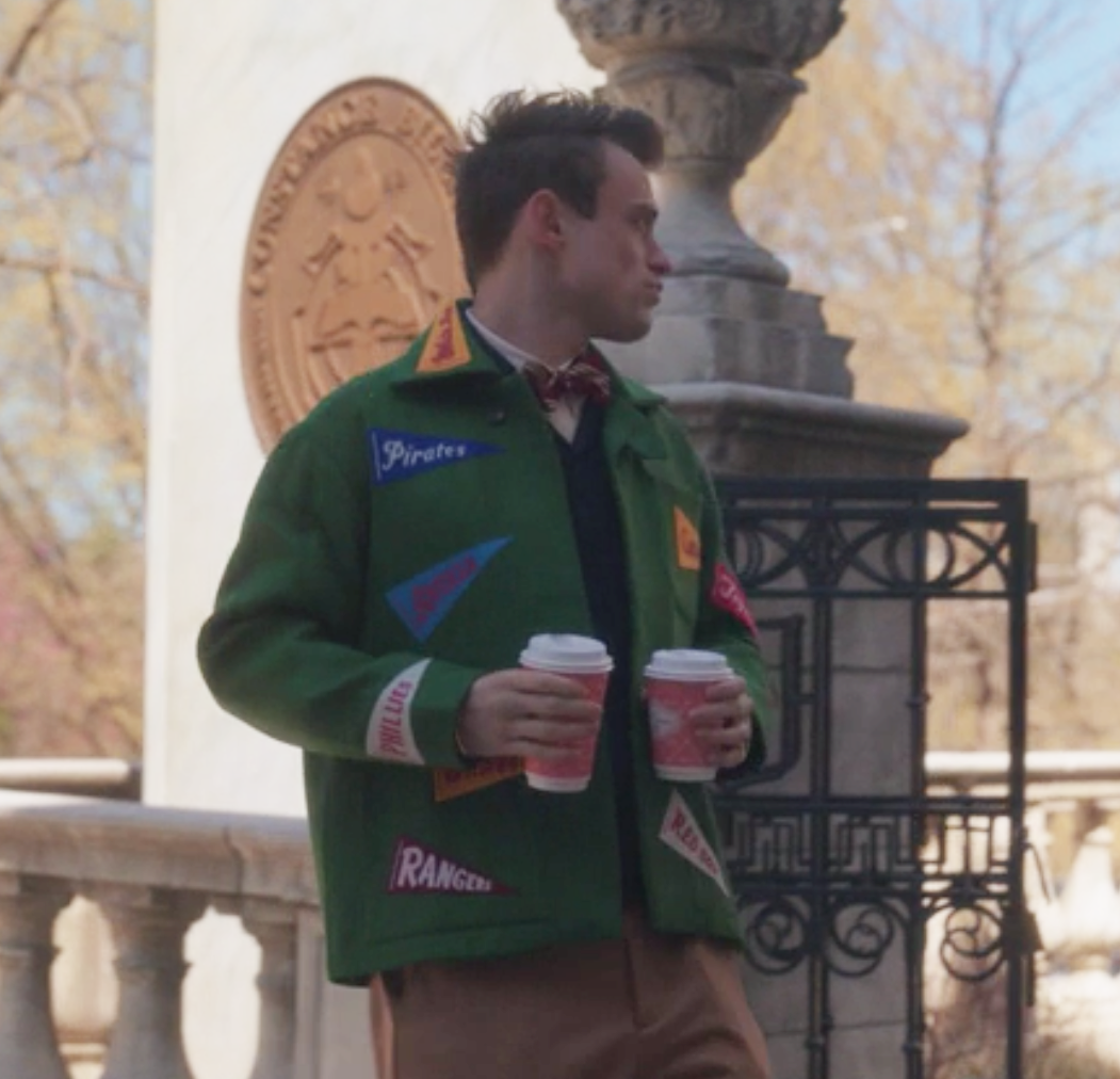 Max wears a wool coat embroidered with baseball team flags