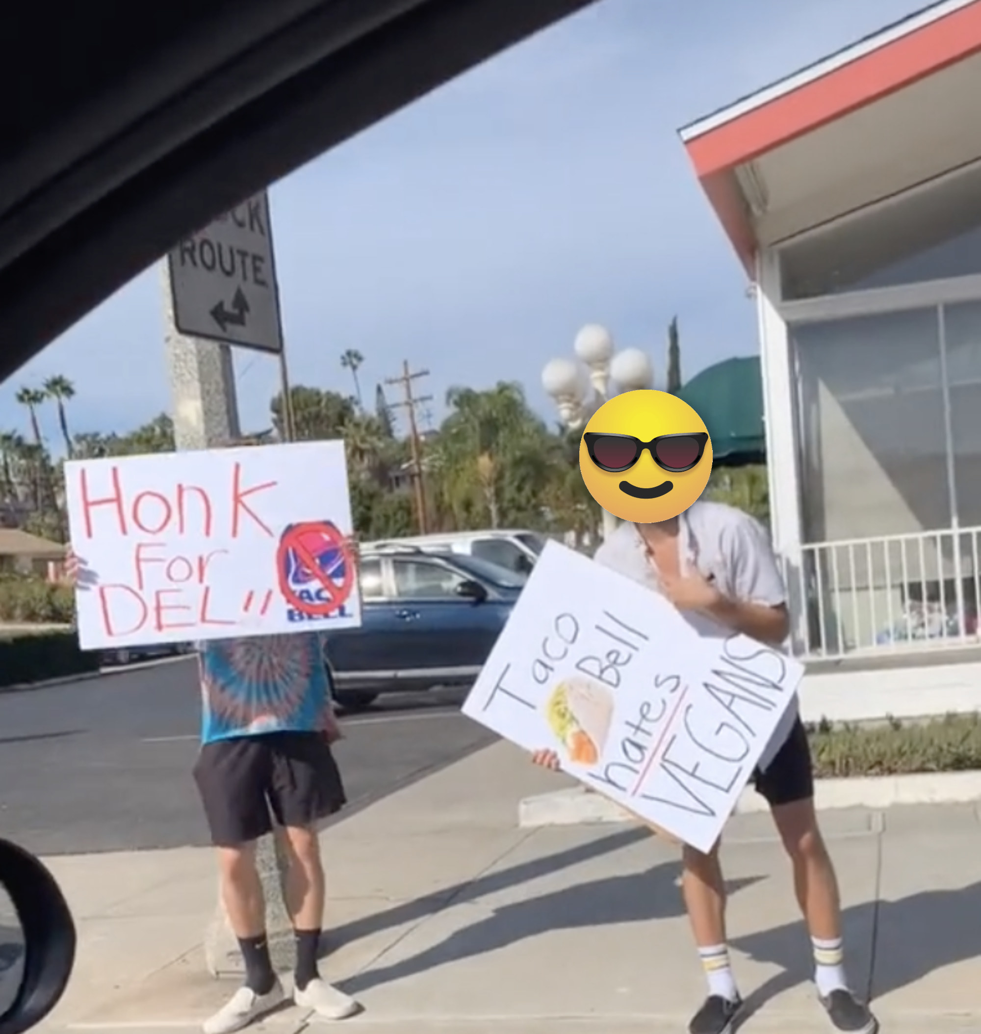 A man holds a sign that says &quot;Taco Bell hates Vegans&quot; on the side of a road